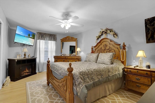 207 SW Rose Ln, Fort White, FL 32038 - bedroom featuring light wood-style floors, a ceiling fan, and a glass covered fireplace