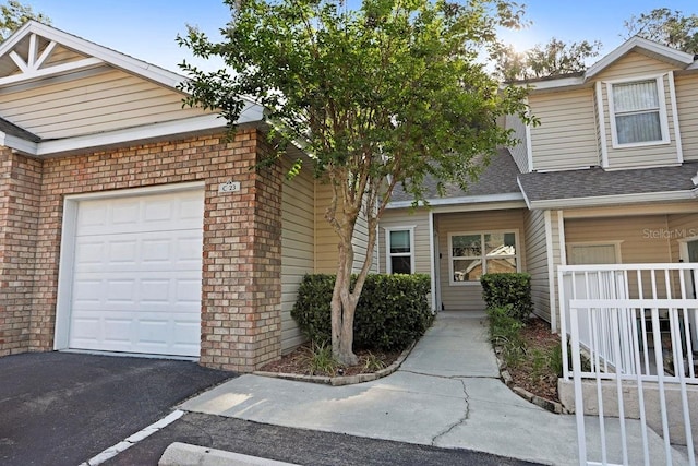 4700 SW Archer Rd Unit 23, Gainesville, FL 32608 - townhome / multi-family property featuring an attached garage, a shingled roof, and brick siding