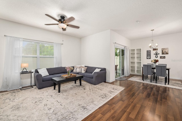living room with a textured ceiling, ceiling fan with notable chandelier, baseboards, and wood finished floors