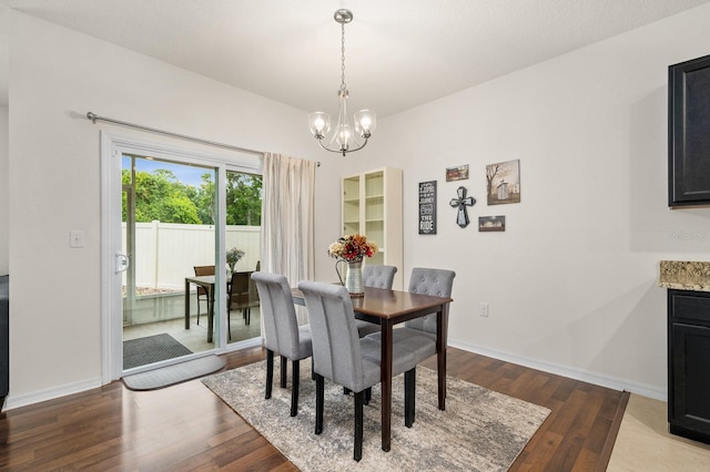 dining room featuring wood finished floors, baseboards, and a notable chandelier