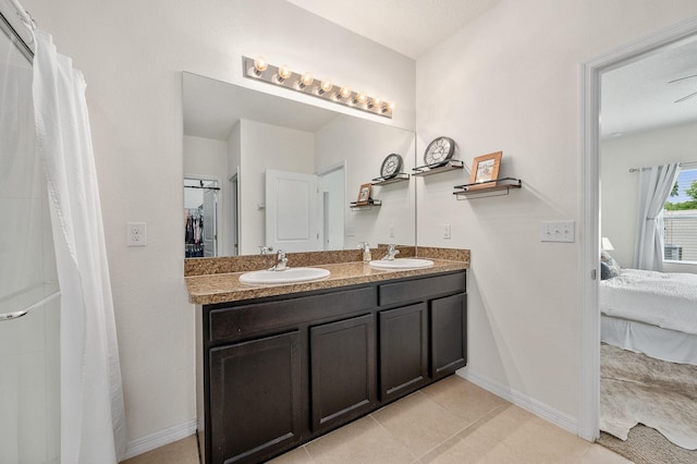 full bathroom with double vanity, ensuite bathroom, baseboards, and a sink