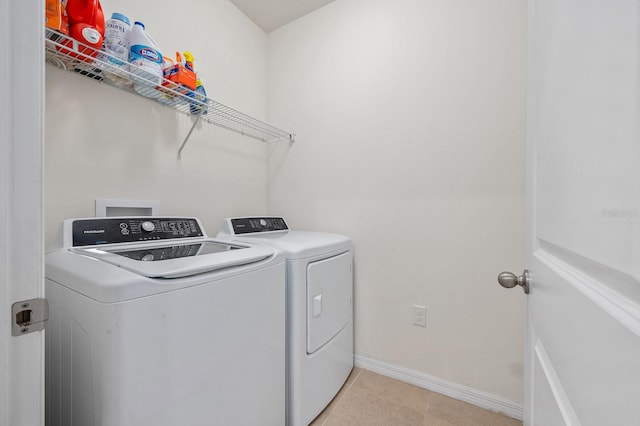 clothes washing area with baseboards, laundry area, light tile patterned flooring, and washer and dryer
