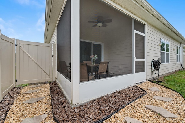view of patio with a gate, ceiling fan, a sunroom, and fence