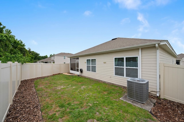 back of property featuring central AC unit, a lawn, and a fenced backyard