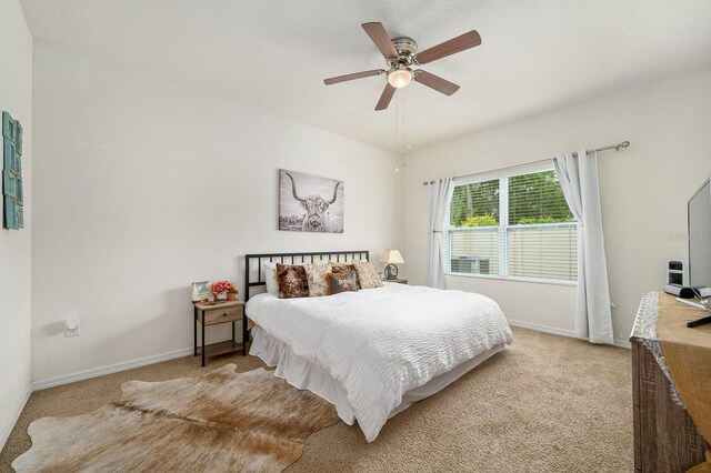 bedroom with ceiling fan, light carpet, and baseboards