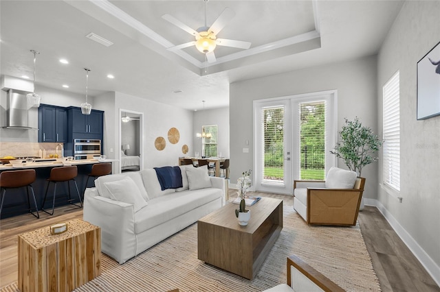 living room featuring light wood-style floors, a raised ceiling, ceiling fan, recessed lighting, and baseboards
