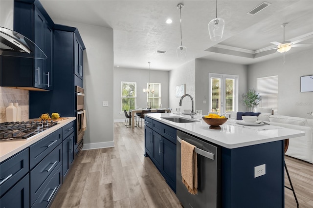 kitchen with appliances with stainless steel finishes, blue cabinetry, a sink, open floor plan, and recessed lighting