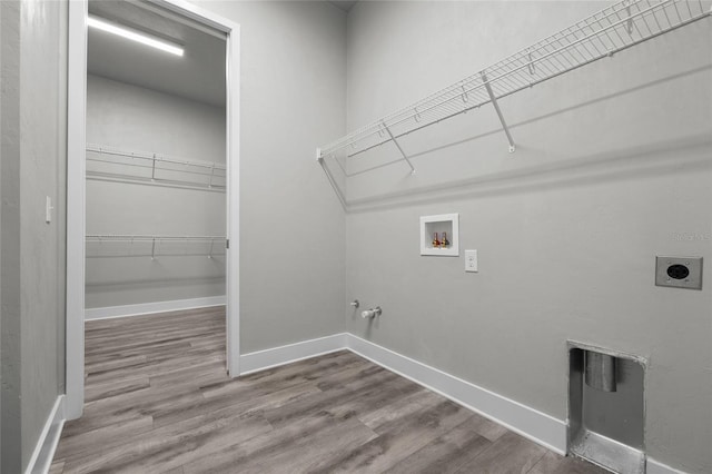 clothes washing area with hookup for a washing machine, gas dryer hookup, wood finished floors, electric dryer hookup, and baseboards