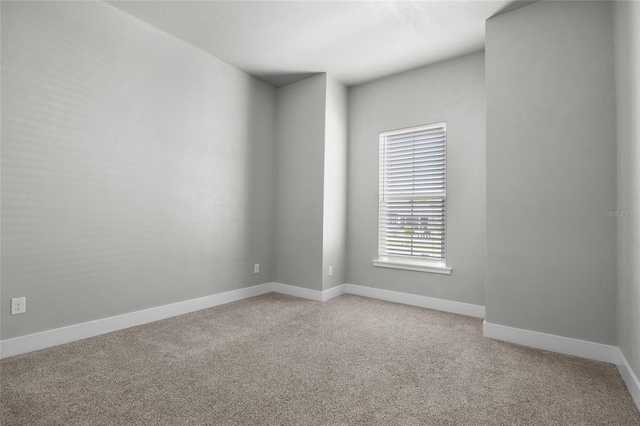 empty room featuring light colored carpet and baseboards