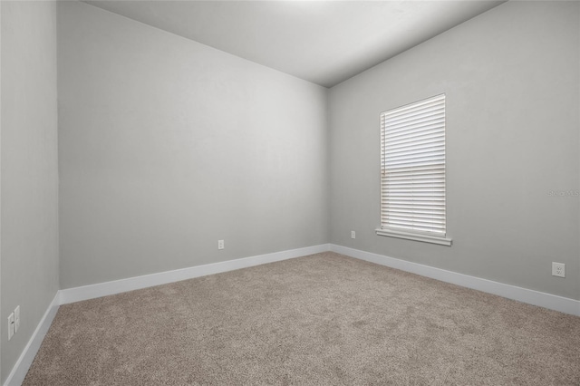 empty room with carpet flooring, baseboards, and lofted ceiling