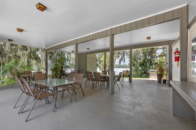 sunroom featuring outdoor dining space and concrete flooring