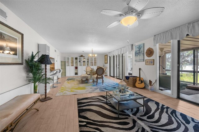 living area featuring wood finished floors, a textured ceiling, a chandelier, and ceiling fan