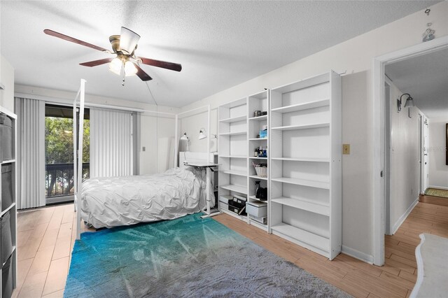 bedroom with light wood-style flooring, baseboards, a textured ceiling, and a ceiling fan