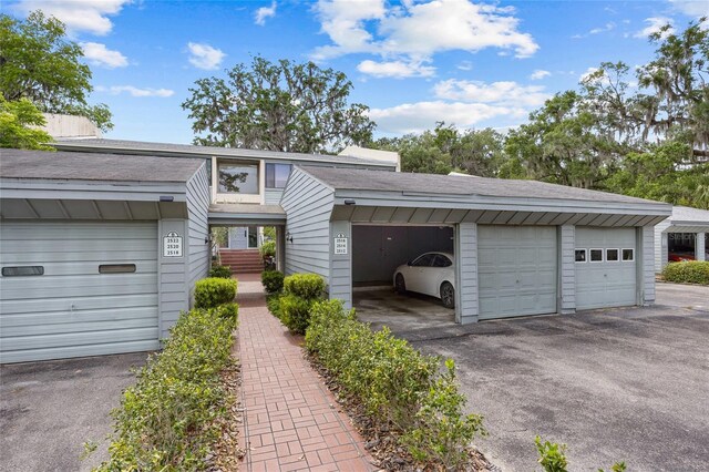 view of property with community garages and roof with shingles