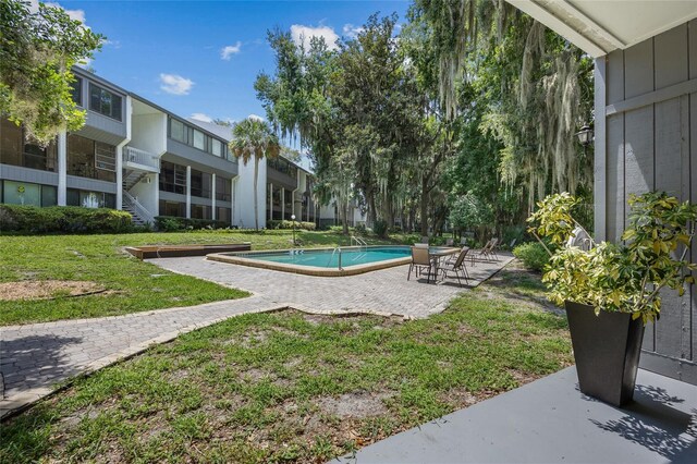 community pool with a patio area and a lawn