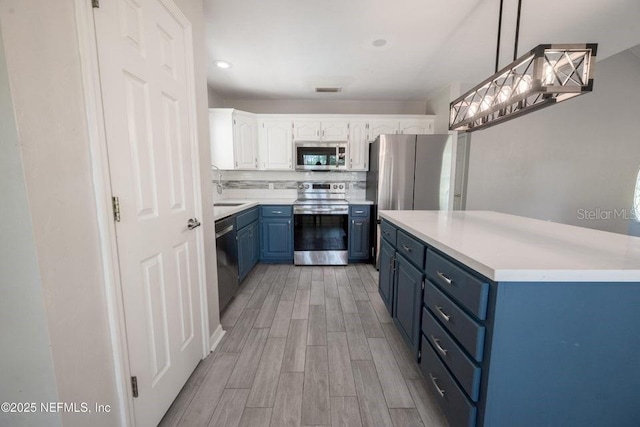 11802 SW 83rd Dr, Lake Butler, FL 32054 - kitchen featuring a sink, stainless steel appliances, white cabinetry, light countertops, and blue cabinetry