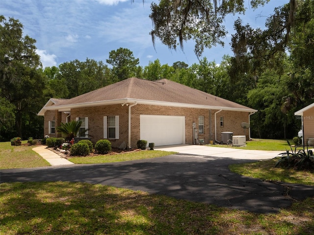 10712 SW 12th Ter, Micanopy, FL 32667 - view of front of home featuring driveway, brick siding, central AC unit, a garage, and a front lawn