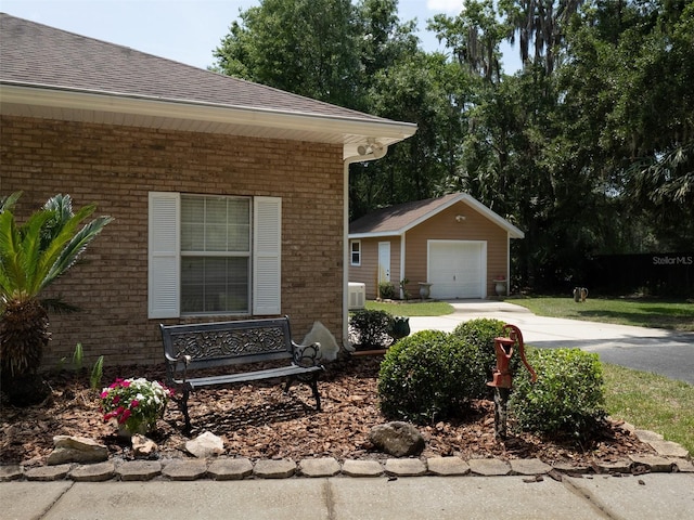 10712 SW 12th Ter, Micanopy, FL 32667 - view of property exterior featuring brick siding, concrete driveway, an outdoor structure, a shingled roof, and a detached garage