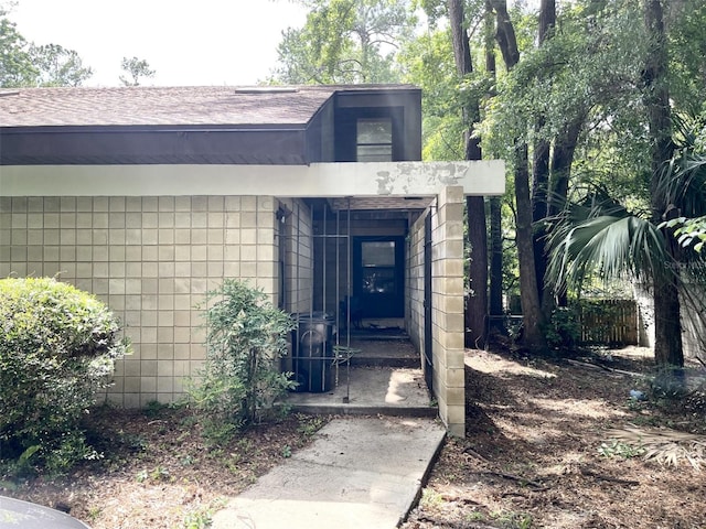 property entrance featuring a shingled roof