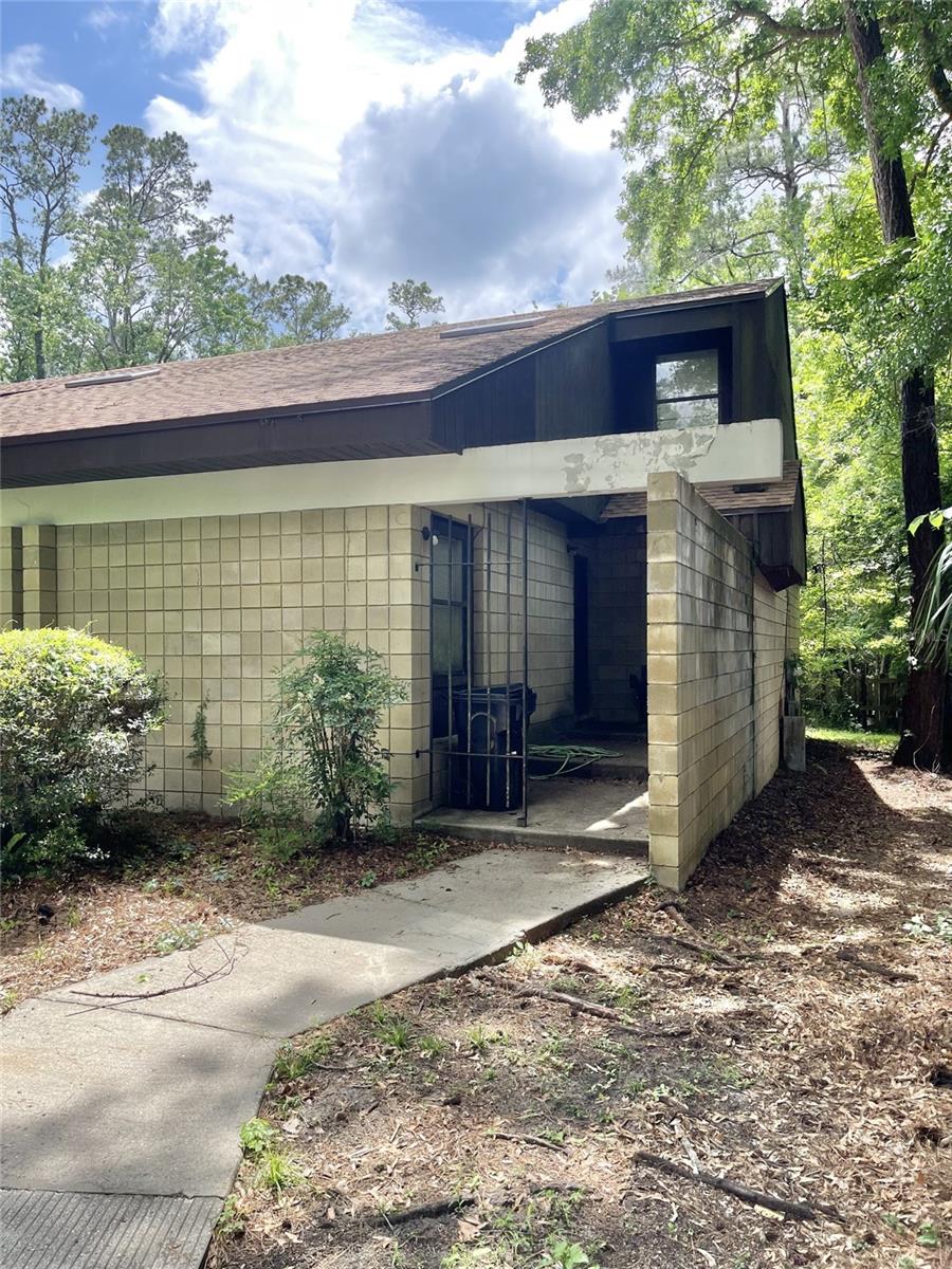 view of side of home featuring concrete block siding and a shingled roof