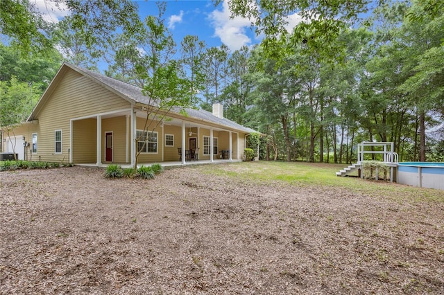 rear view of property featuring a chimney and an outdoor pool