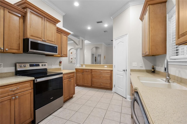 kitchen with stainless steel appliances, a sink, ornate columns, arched walkways, and light countertops