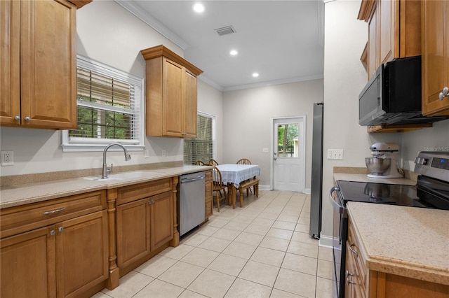 kitchen with appliances with stainless steel finishes, a sink, crown molding, light countertops, and light tile patterned flooring