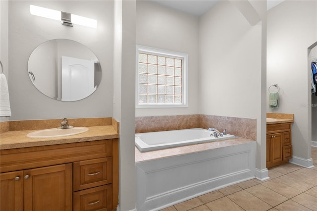 full bath featuring tile patterned flooring, two vanities, a garden tub, and baseboards