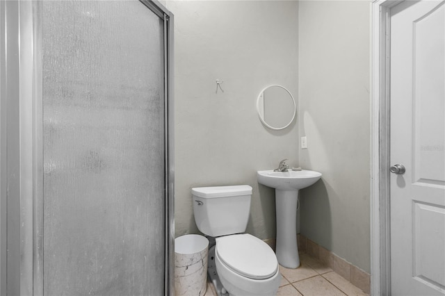 full bath featuring tile patterned flooring, toilet, a sink, a shower with shower door, and baseboards