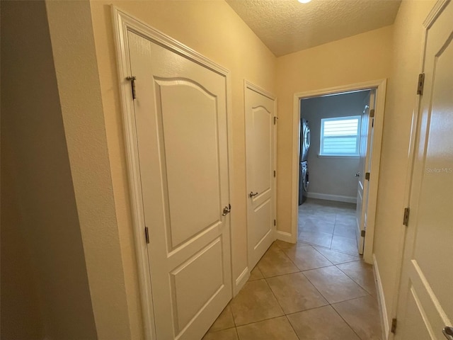 8216 NW 54th St, Gainesville, FL 32653 - corridor featuring stacked washer / dryer, a textured ceiling, light tile patterned floors, and baseboards