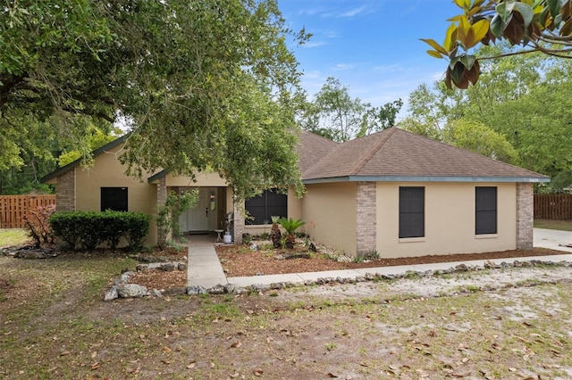 single story home featuring fence, stucco siding, and roof with shingles