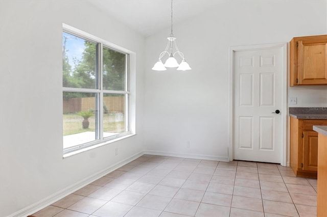 unfurnished dining area with a chandelier, light tile patterned floors, and baseboards