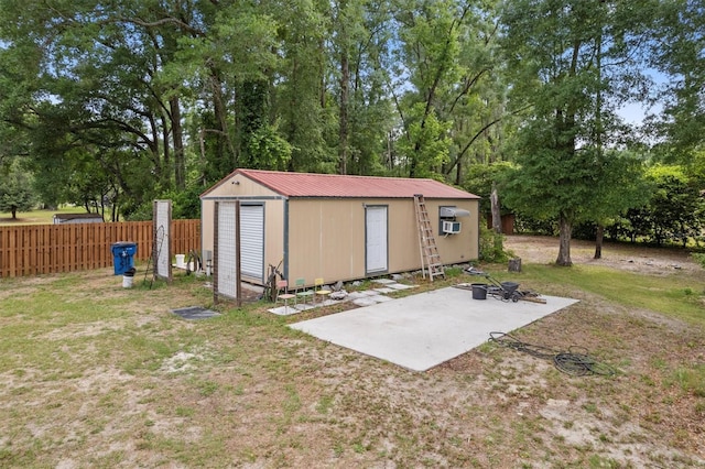 view of outdoor structure featuring fence, an outdoor structure, and view of wooded area