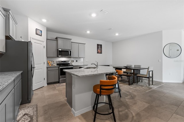 5237 NW 48th Pl, Ocala, FL 34482 - kitchen featuring appliances with stainless steel finishes, gray cabinetry, recessed lighting, a breakfast bar area, and a center island with sink