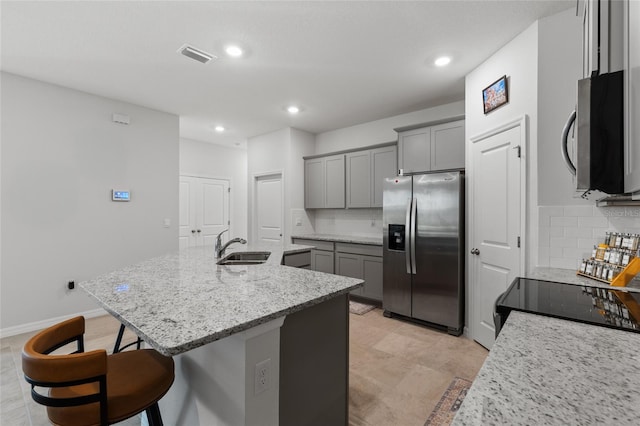 5237 NW 48th Pl, Ocala, FL 34482 - kitchen featuring appliances with stainless steel finishes, gray cabinets, backsplash, a center island with sink, and a kitchen breakfast bar