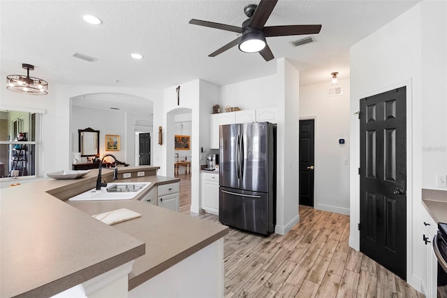 23510 Oak Prairie Cir, Sorrento, FL 32776 - kitchen featuring freestanding refrigerator, a sink, arched walkways, ceiling fan, and white cabinets