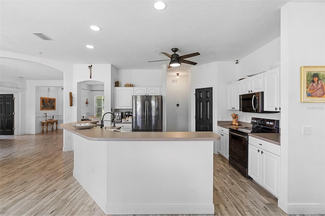 23510 Oak Prairie Cir, Sorrento, FL 32776 - kitchen featuring stainless steel appliances, arched walkways, white cabinets, light wood-style floors, and a textured ceiling