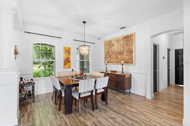 23510 Oak Prairie Cir, Sorrento, FL 32776 - dining area featuring light wood-type flooring, arched walkways, a chandelier, and ornate columns