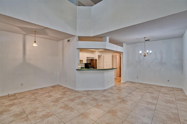 kitchen with freestanding refrigerator, light tile patterned flooring, a chandelier, dark countertops, and a towering ceiling