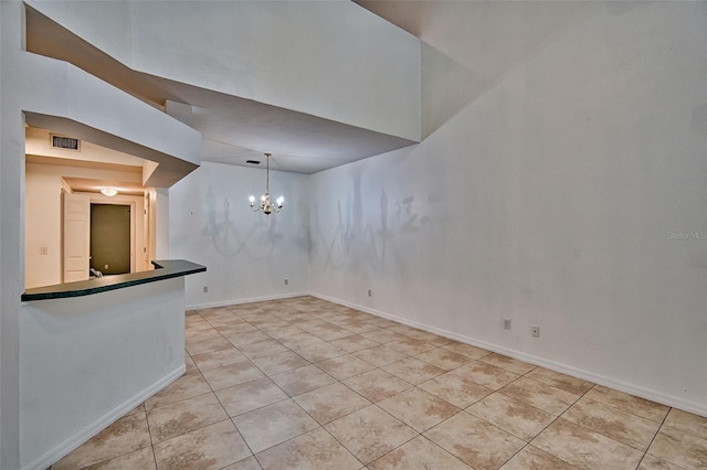 spare room with light tile patterned floors, a chandelier, and baseboards