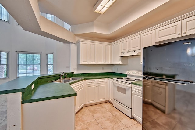 kitchen featuring electric stove, freestanding refrigerator, a sink, under cabinet range hood, and dark countertops