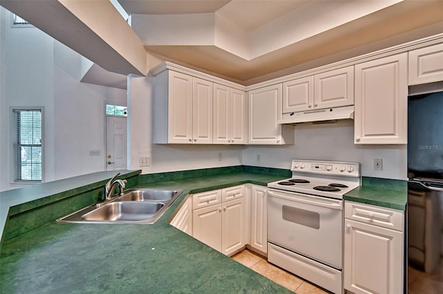 kitchen with electric range, under cabinet range hood, a sink, freestanding refrigerator, and dark countertops