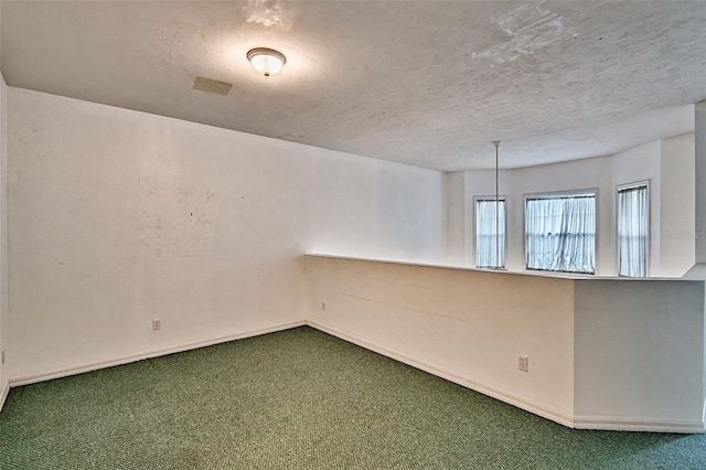 unfurnished room with carpet, baseboards, and a textured ceiling