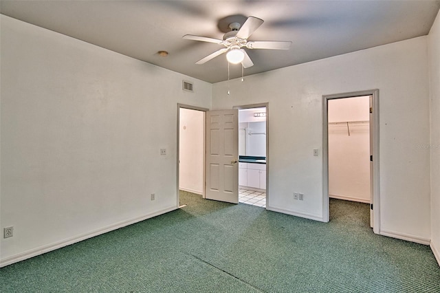 unfurnished bedroom with carpet floors, a spacious closet, baseboards, ensuite bath, and a closet