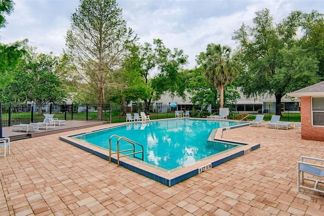community pool with a patio area and fence