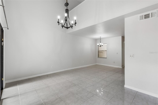 unfurnished dining area featuring a chandelier, baseboards, tile patterned floors, and a towering ceiling