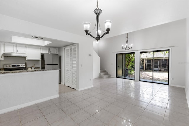 unfurnished living room featuring a chandelier, light tile patterned flooring, stairway, and baseboards