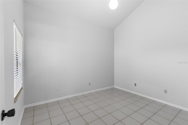 spare room with healthy amount of natural light, baseboards, and light tile patterned flooring