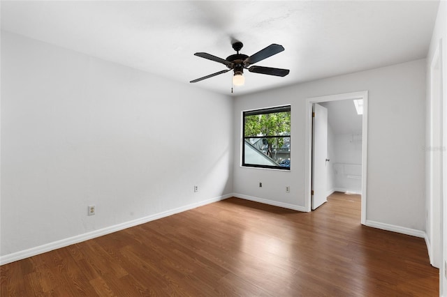 unfurnished bedroom with wood finished floors, a spacious closet, baseboards, ceiling fan, and a closet
