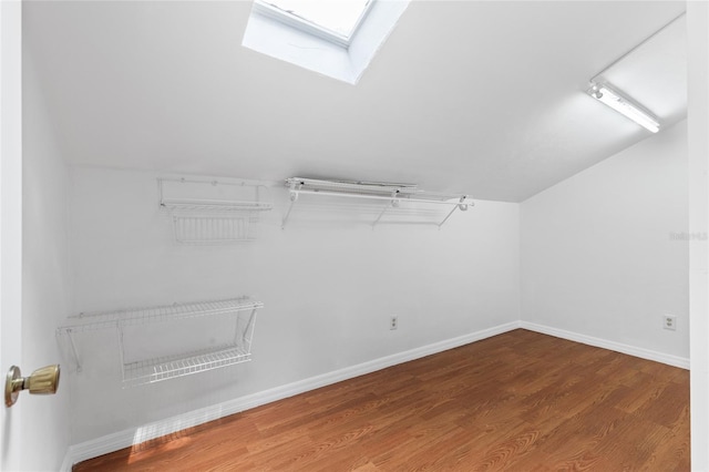 spacious closet featuring wood finished floors, a skylight, and vaulted ceiling